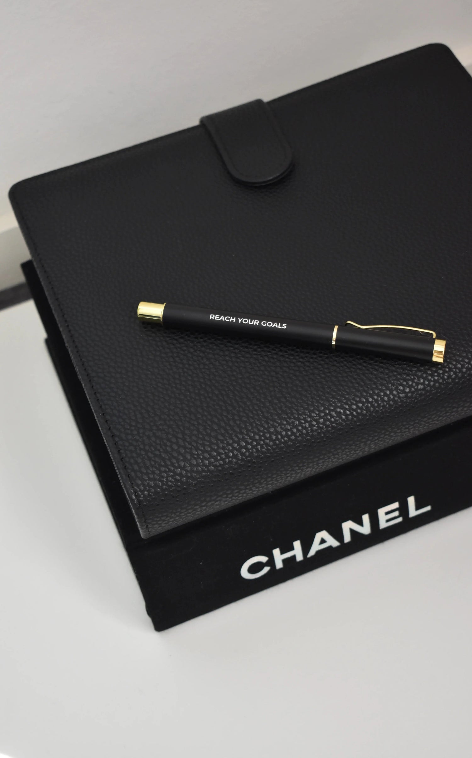 Zwarte rollerbal pen van Vaye Amsterdam met reach your goals op de pen. De pen is zwart en heeft gouden details.